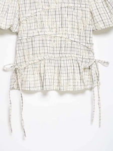 Detail of floral embroidery on black and white checkered puff sleeve top with side drawstrings