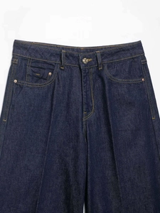 Detail of high-waist dark blue denim jeans showing metal button and yellow stitching