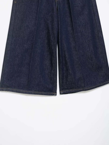 Detailed view of dark blue denim wide-leg pants featuring yellow contrast topstitching