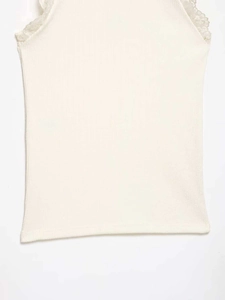 Detail of cream sleeveless ribbed vest showing delicate lace trim on the neckline
