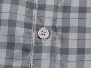 Macro detail of grey plaid pattern fabric with resin buttons and neat stitching