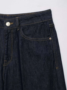 Detail view of high-quality dark blue denim waist with metal button and rivets