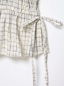 Detail of checkered fabric featuring raw edges, 3D embroidery, and drawstring waist design