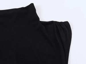 Detail of shoulder ruching and mock neck on black knitted asymmetric pleated dress
