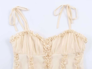 Detail of ruffle trim and bow tie straps on this cream-colored lace camisole top