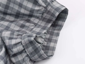 Detail of grey gingham fabric texture and pleated ruffle design on a mini dress