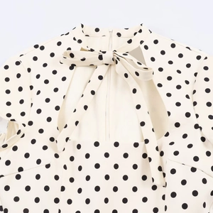 Detailed view of polka dot dress featuring a high neck bow tie and open back cutout
