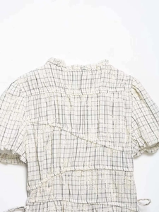 Detailed macro view of off-white plaid embroidery fabric with ruffle collar and floral texture