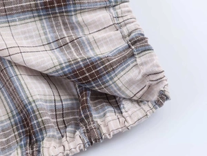 Detailed macro shot of the plaid fabric texture and elastic hem with fine stitching