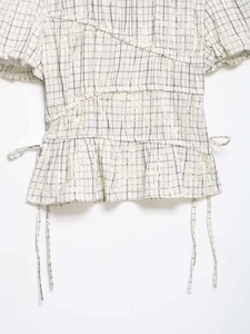 Detail of floral lace embroidery and drawstring waist on a black and white checkered top