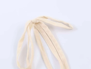Close-up of beige ruffled lace straps with soft woven texture on a summer camisole