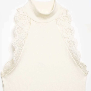 Elegant sleeveless knit top in cream white with mock neck and delicate lace trim