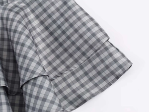 Detail of grey gingham pattern and layered ruffles on a summer mini dress fabric