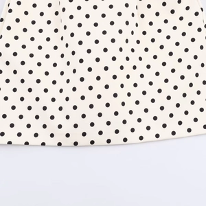 Close-up of ivory white fabric with classic black polka dots showing smooth texture