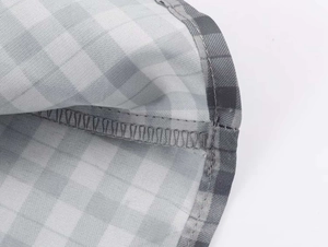 Detailed close-up showing precise overlock stitching on grey gingham checkered fabric