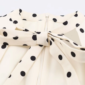 Detailed view of polka dot dress neck featuring large bow tie and hidden back zipper