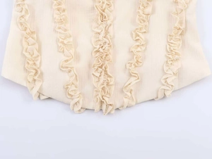 Detail of beige lace camisole featuring vertical ruffled edges and textured fabric