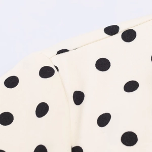 Detail view of cream polka dot dress fabric showing high-quality stitching and texture