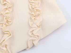Close-up of cream lace tank top featuring delicate ruffle trim and textured stripe fabric
