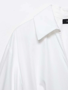 Detail of the white shirt dress collar showing the inner brand label and crisp cotton fabric