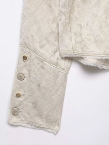 Detail of vintage jacquard jacket with metallic buttons and frayed edge finish