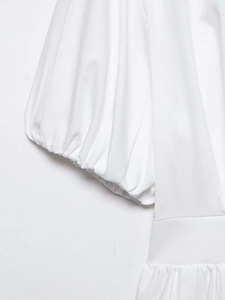 Detail of white shirt dress showing puffed sleeves and elastic smocked waist texture