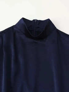 Détail d'une robe en satin bleu marine avec col montant élégant et fermeture éclair discrète