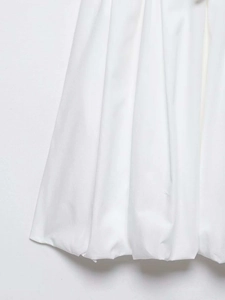 Detail of white shirt dress featuring vertical pleats and a unique bubble hem design