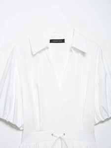 Detailed view of white V-neck dress with puff sleeves and adjustable drawstring waist