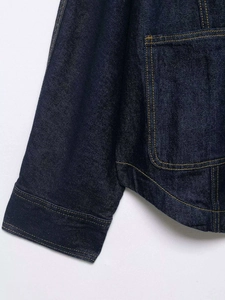 Detailed view of the dark blue denim jacket stitching with contrasting yellow thread