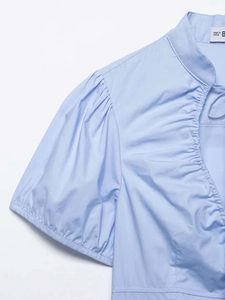 Detail of light blue puff sleeve poplin shirt showing neckline and fabric texture