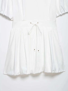 Detail of white puff sleeve dress featuring a drawstring waist with gold metal eyelets
