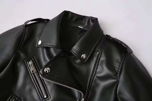 Détails d'une veste motard noire en cuir avec fermetures éclair argentées et boutons pression