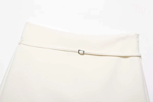 Detail of high-waist white A-line skirt featuring a slim belt with a metal square buckle