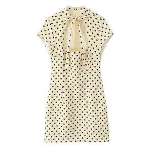 Detailed back view of a beige polka dot mini dress featuring a cutout design and bow tie knot