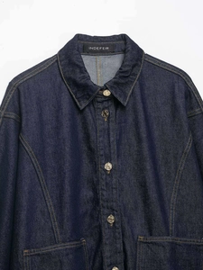 Detail of dark blue heavy denim shirt featuring yellow stitching and bronze buttons