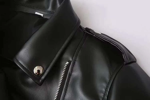 Détail d'un blouson motard en cuir noir avec des fermetures éclair argentées et des épaulettes