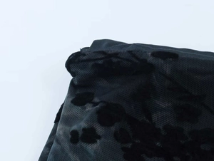 Dettaglio del tessuto a rete nero con intricati motivi floreali in velluto floccato