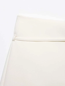 Macro detail of high-waist white woven skirt showing fine texture and waistband loop