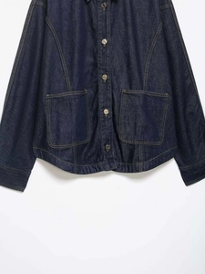 Detail view of deep blue denim jacket with contrast stitching and metallic buttons