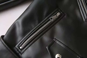 Gros plan sur les fermetures éclair argentées et coutures de veste en cuir PU noir