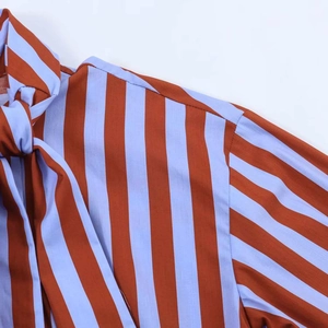 Detailed close-up of striped long-sleeve shirt with bow tie neckline and fabric texture