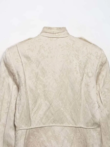 Close-up of beige jacquard jacket featuring intricate floral texture and stand collar