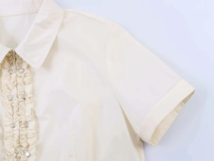 Detail of ruffle trim short sleeve shirt with metal snap buttons and zipper closure