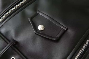 Détail de la texture cuir noir avec fermeture éclair métallique et bouton argenté poli