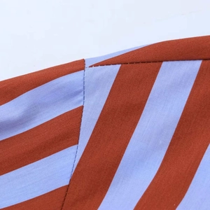 Close-up of red-brown and light blue striped shirt showing shoulder seam and fabric texture