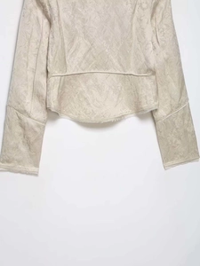 Detail of white jacquard jacket fabric with floral textures and raw fringe hem