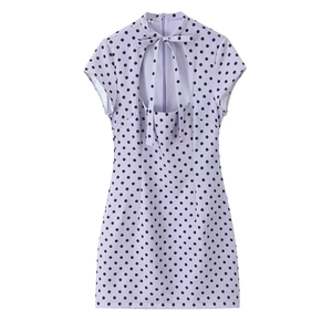 Macro view of purple polka dot dress featuring a bow tie neckline and hollow out detail