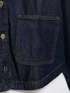 Detailed close-up of dark blue denim jacket featuring contrast yellow stitching and metal buttons