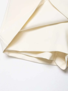 Macro shot of white high-waist skirt showing layered fabric and precise stitching detail